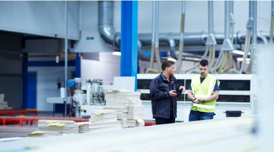 Zwei Beschäftigte in einem Möbelwerk im Gespräch