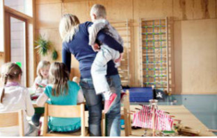 Kindergärtnerin hebt ein Kind