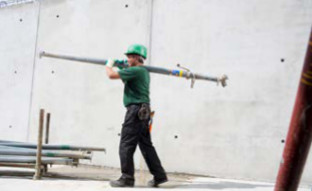 Arbeiter trägt eine Stahlstütze auf einer Schulter