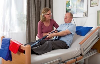 Altenpflegerin hilft Patienten sich aufzurichten