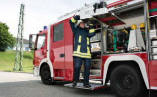 Ein Feuerwehrmann hebt Ausrüstung in Kopfhöhe
