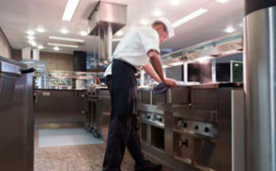 Ein Koch steht gebeugt an der Arbeitsplatte